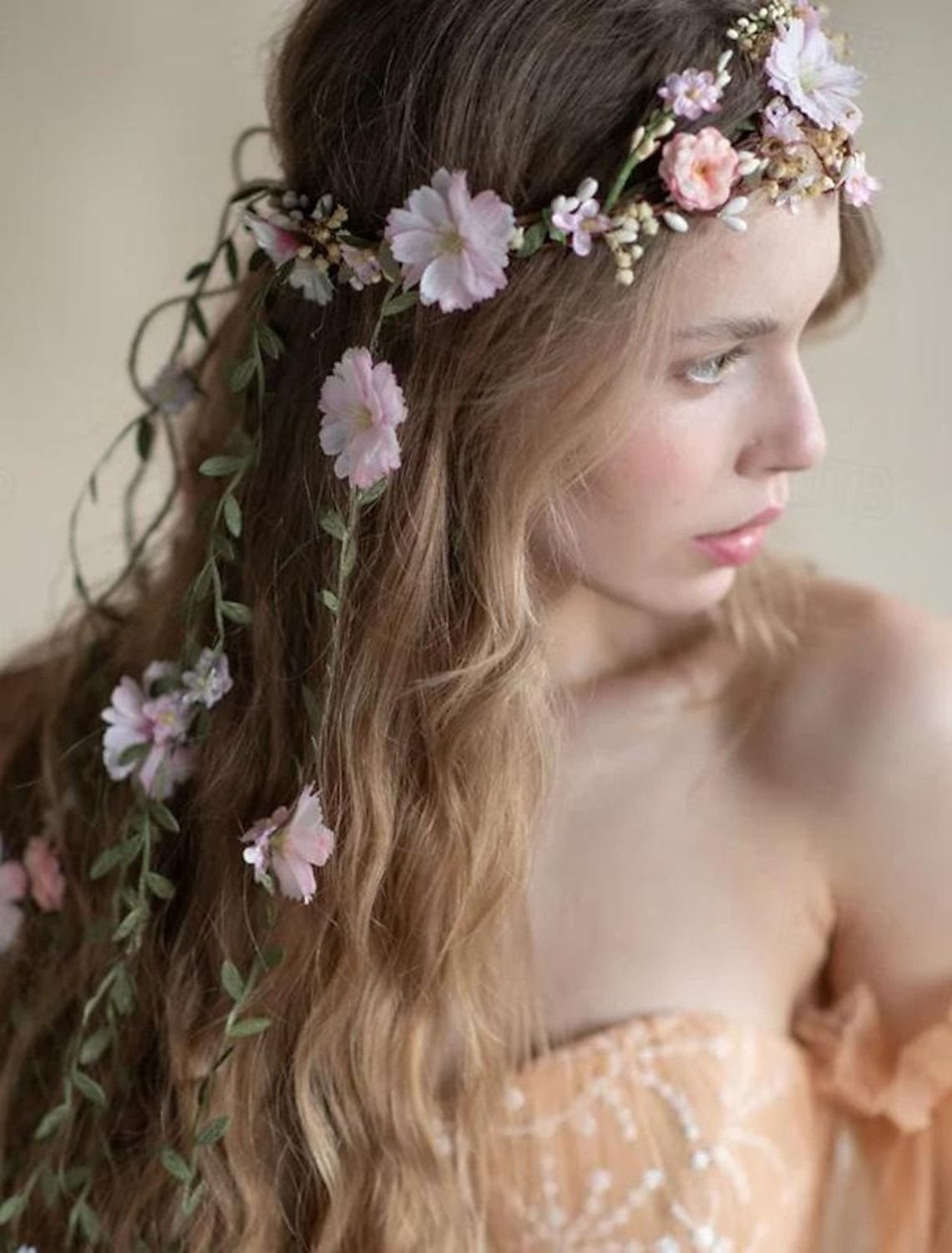 1989 Wedding Dresses: 8 Details That Defined the Look 4 A young woman wearing a delicate crown of pink flowers and trailing green vines in her hair.