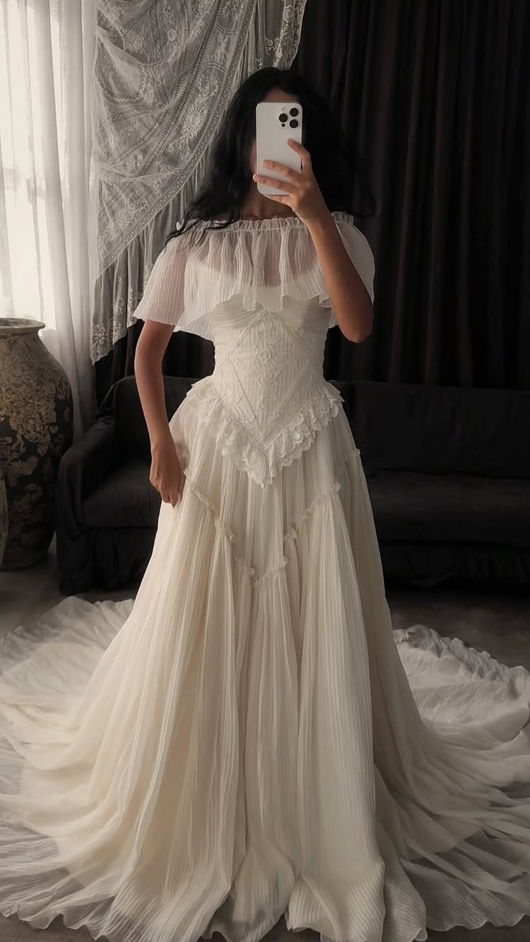 8 Alternative Wedding Dresses for Every Kind of Modern Bride 4 A person wearing a flowing, cream-colored vintage-style wedding dress with a ruffled neckline.