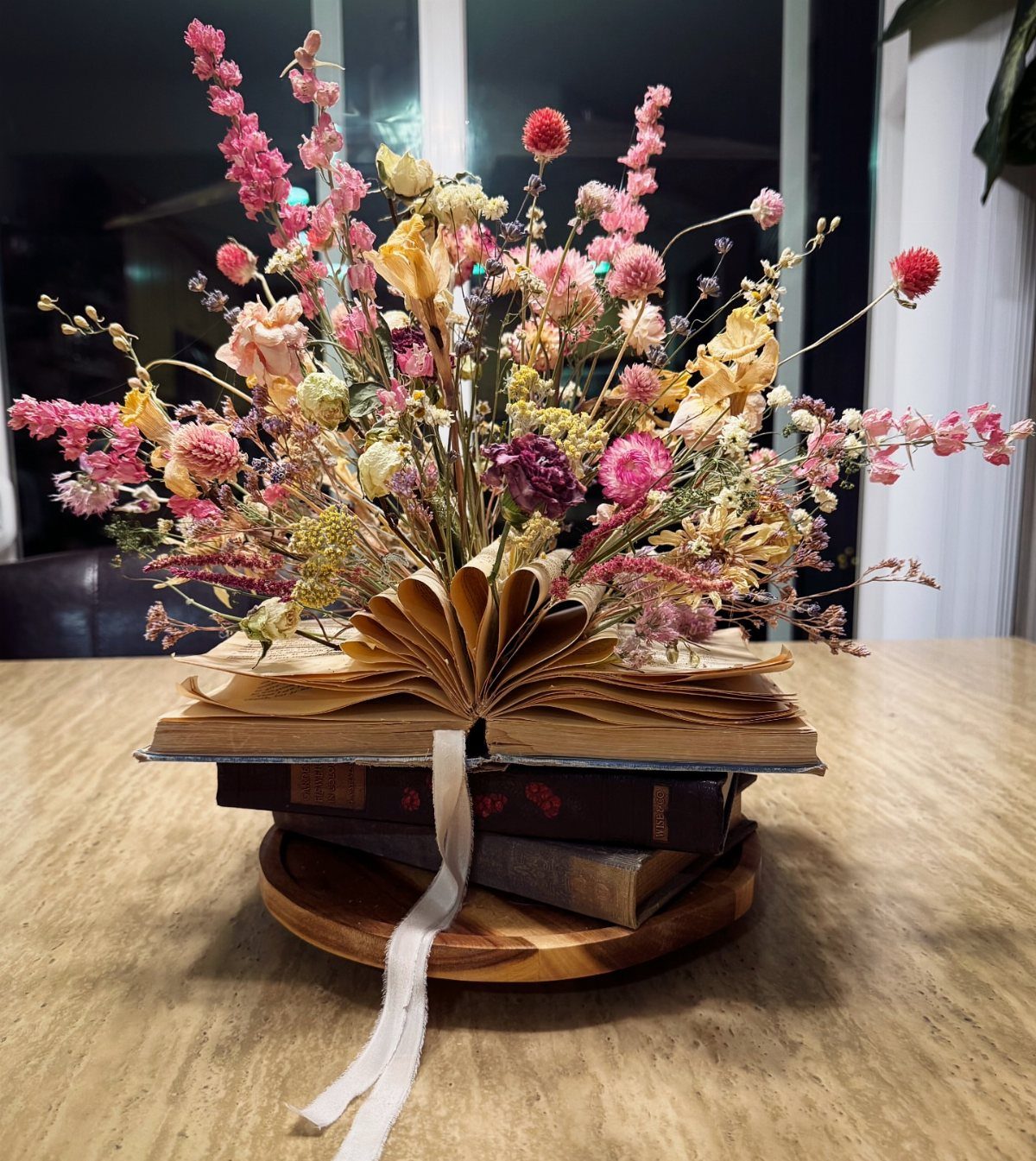 15 Boho Wedding Flowers and Ideas for the Free-Spirited Bride 3 Dried colorful flowers arranged inside the open pages of an old book on a wooden tray.