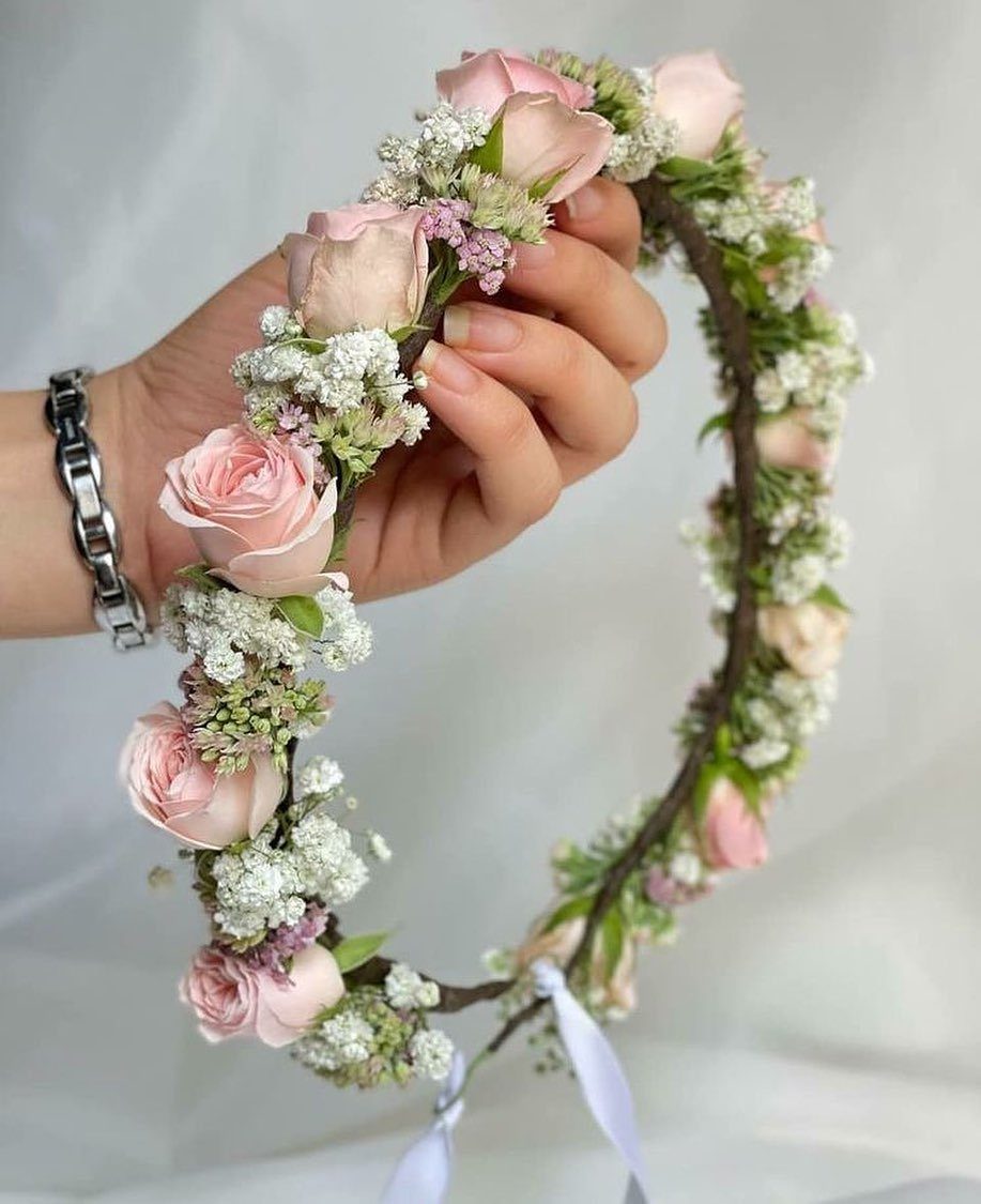 15 Boho Wedding Flowers and Ideas for the Free-Spirited Bride 1 A hand holding a delicate floral crown made of pink roses and white blossoms.
