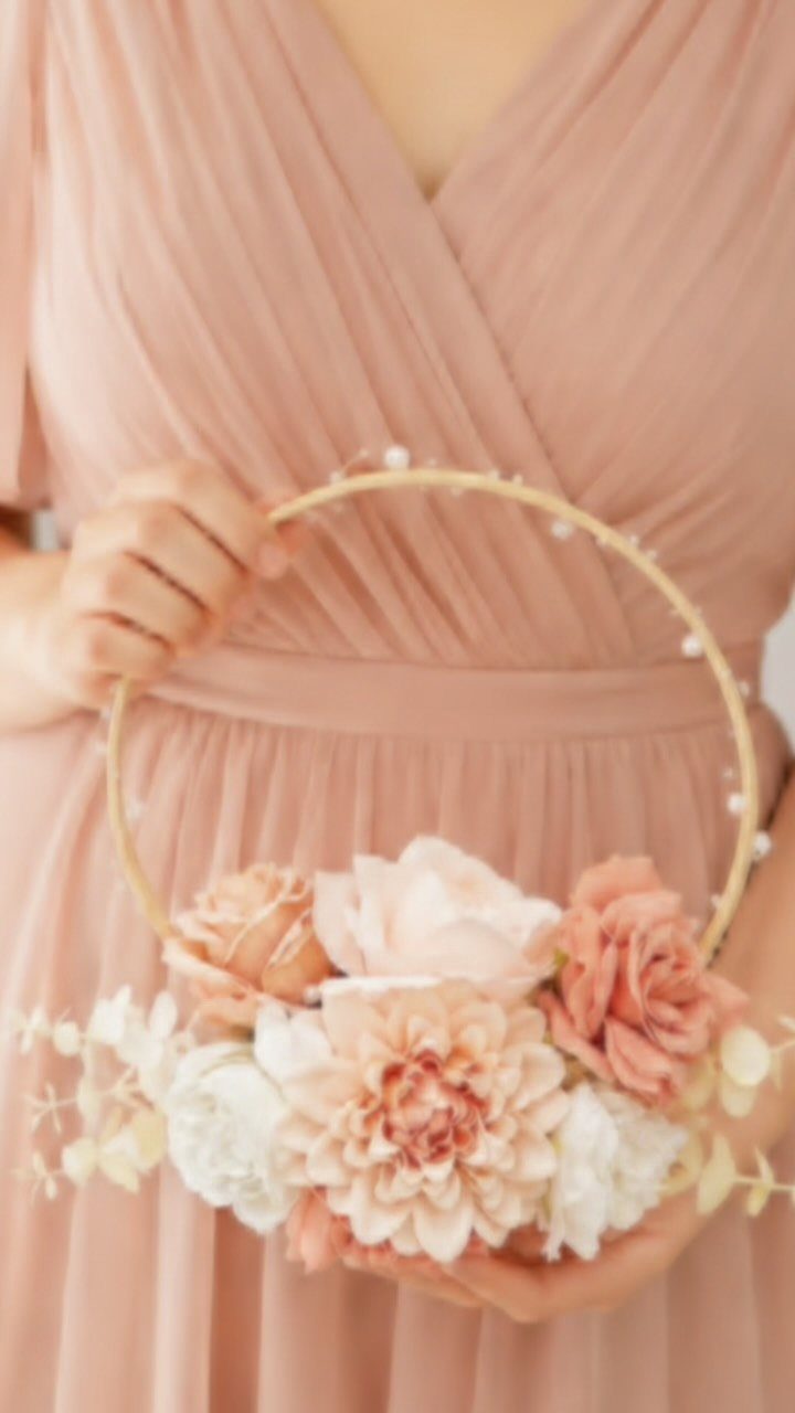 15 Boho Wedding Flowers and Ideas for the Free-Spirited Bride 12 A person holding a circular floral hoop bouquet with peach and white flowers against a rose dress.