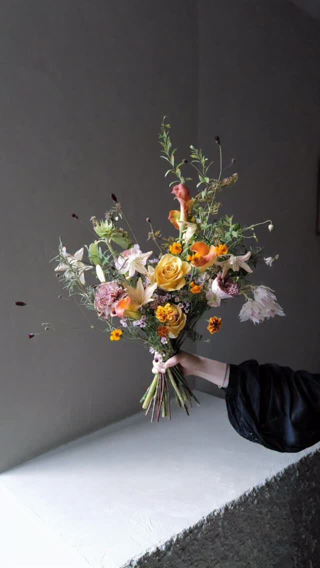 15 Boho Wedding Flowers and Ideas for the Free-Spirited Bride 4 A hand holding a large, colorful wildflower bouquet with yellow roses and lilies.