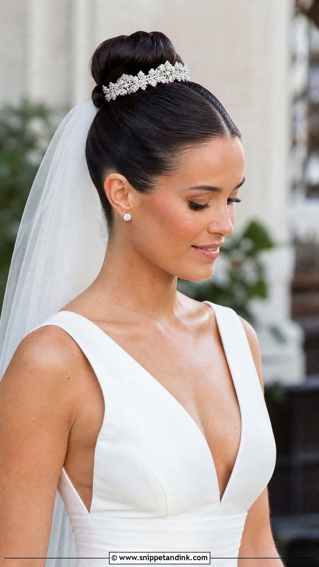 8 Bridal Hair with Veil Ideas for Every Length and Style 2 A woman wearing a sleek high bun with a tiara and a white wedding veil.
