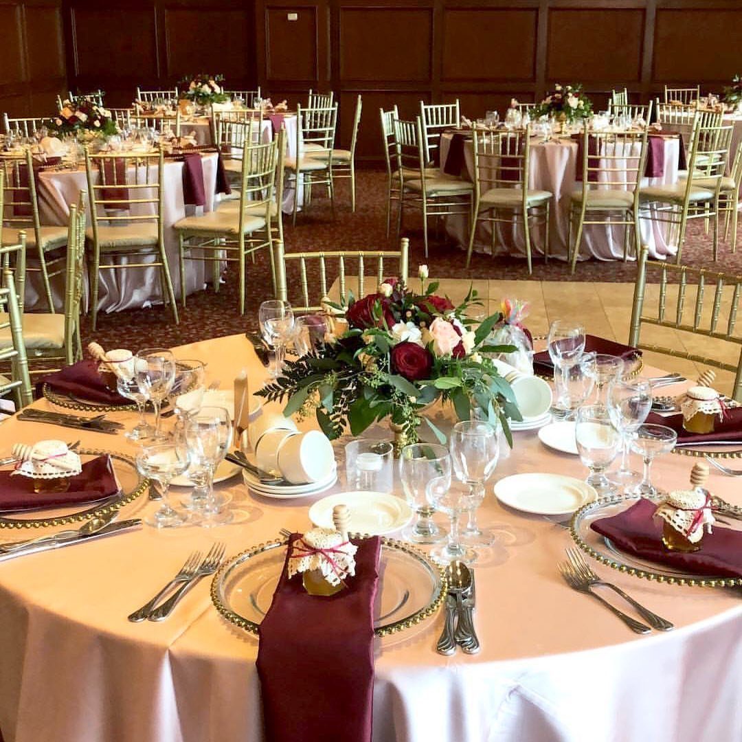 10 Burgundy and Blush Wedding Ideas for Color, Flowers & Decor 1 Wedding table setting featuring blush pink linens, burgundy napkins, and a floral centerpiece with red and pink roses.