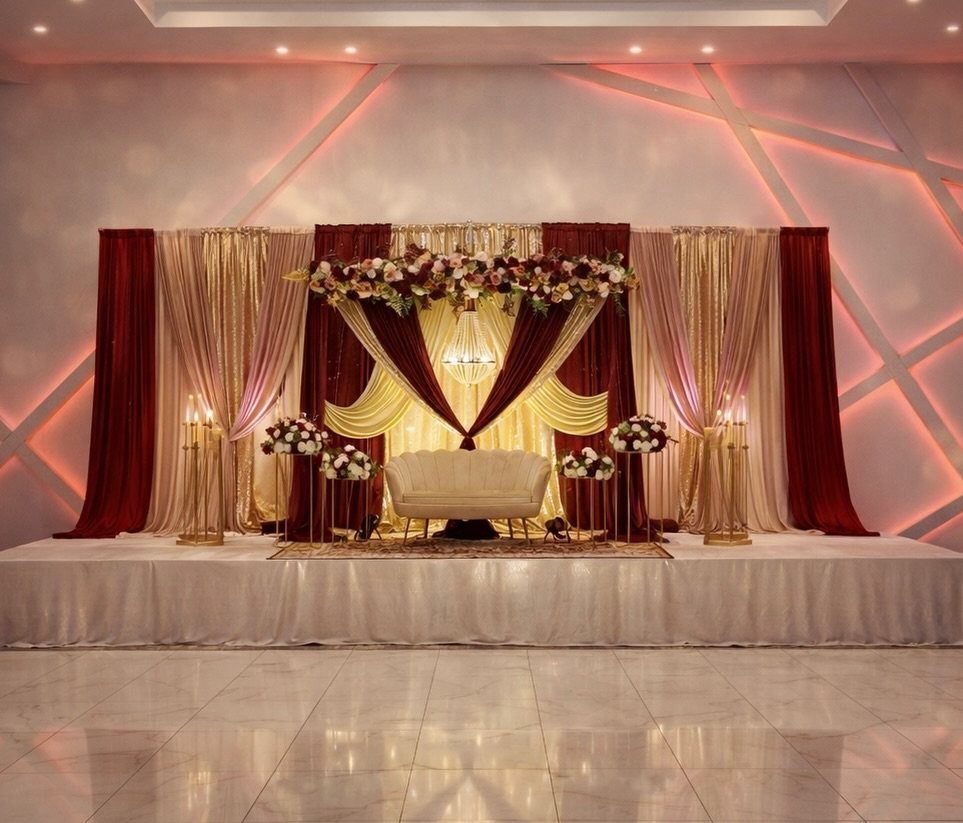 10 Burgundy and Blush Wedding Ideas for Color, Flowers & Decor 8 A wedding stage decorated with burgundy and blush drapes, floral arrangements, and a white sofa.