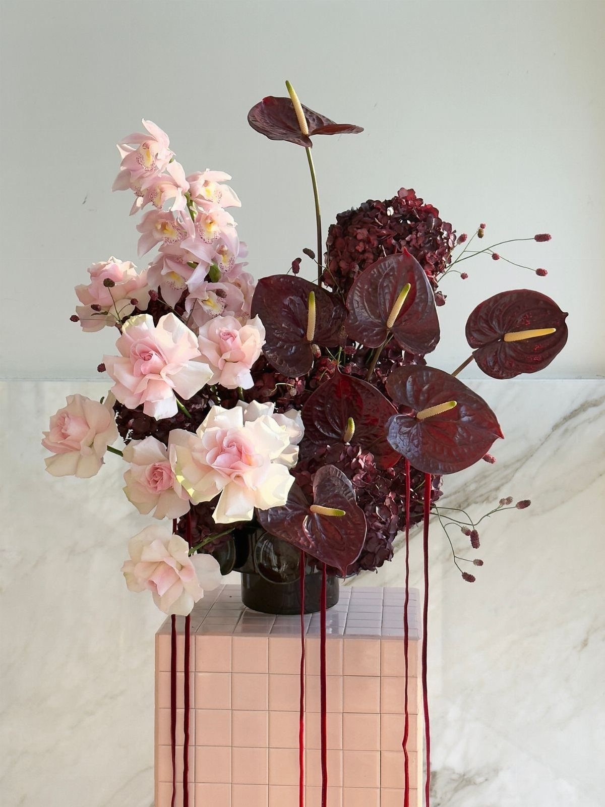 10 Burgundy and Blush Wedding Ideas for Color, Flowers & Decor 10 Floral arrangement with pink roses and burgundy anthuriums with long red ribbons.