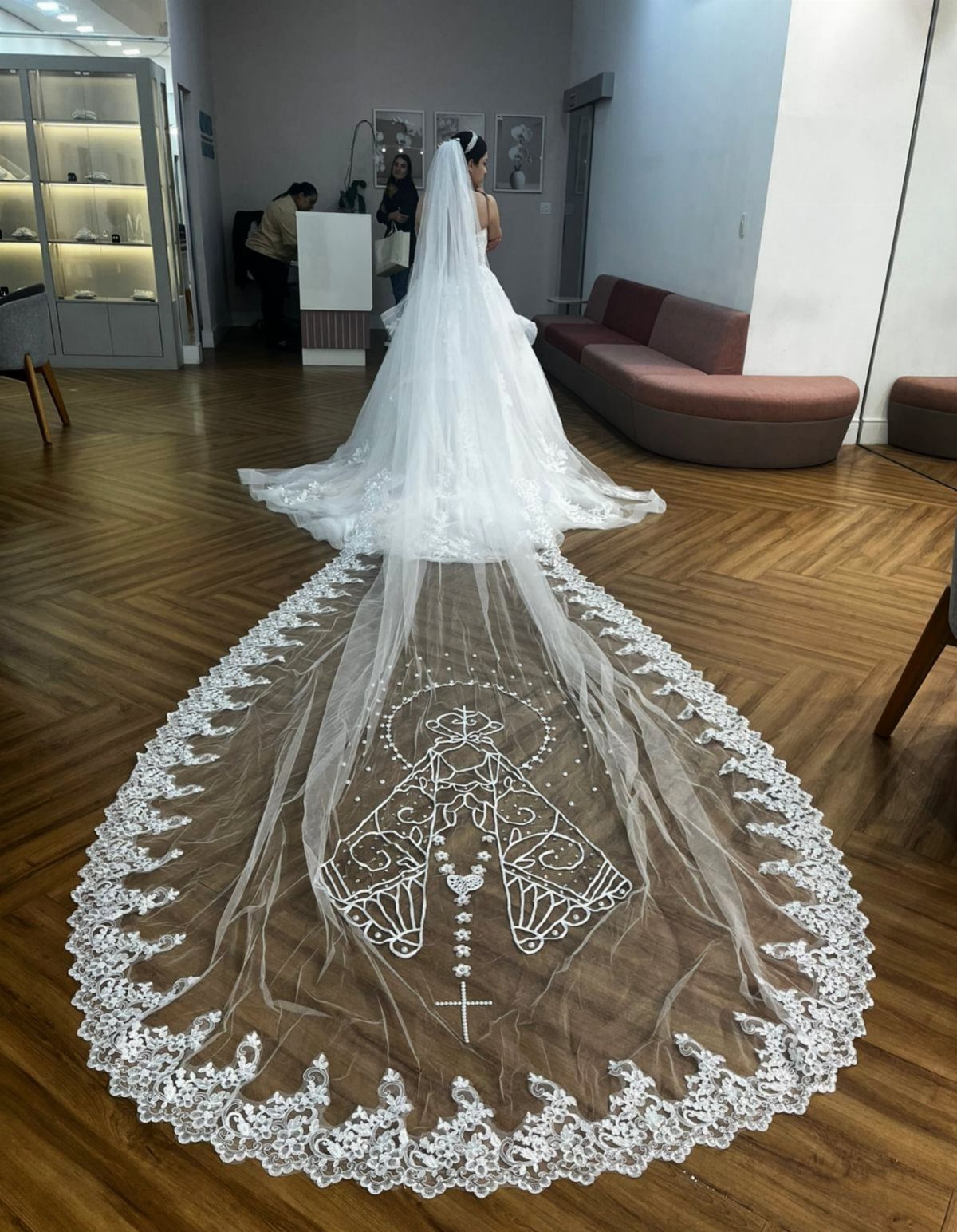 Catholic Wedding Dresses for Modest Church Ceremonies: 6 Ideas 3 A bride wearing a long white wedding dress with an expansive, lace-embroidered cathedral veil.