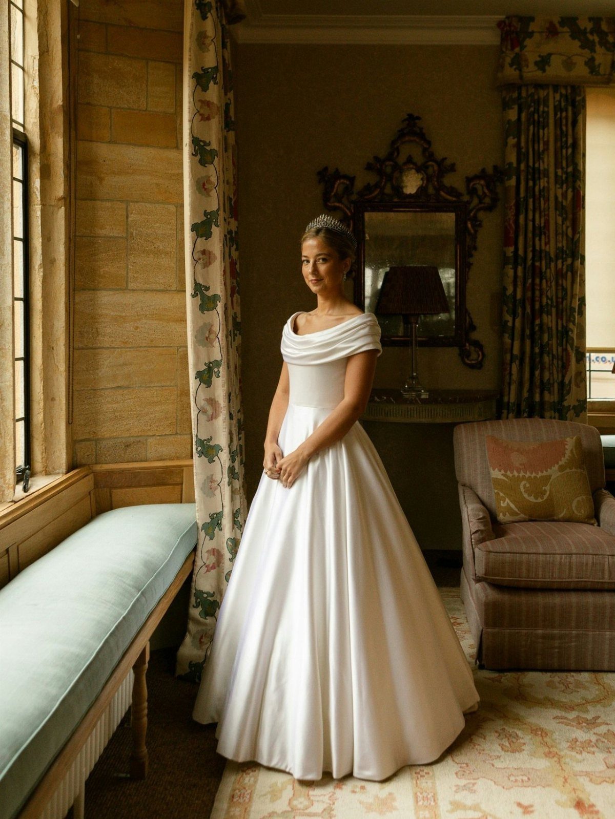Catholic Wedding Dresses for Modest Church Ceremonies: 6 Ideas 2 A woman in a white satin A-line wedding dress standing in a sunlit room.