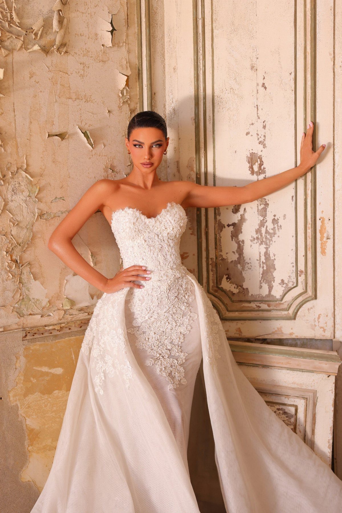 Woman in a white lace wedding dress with a large detachable overskirt train.