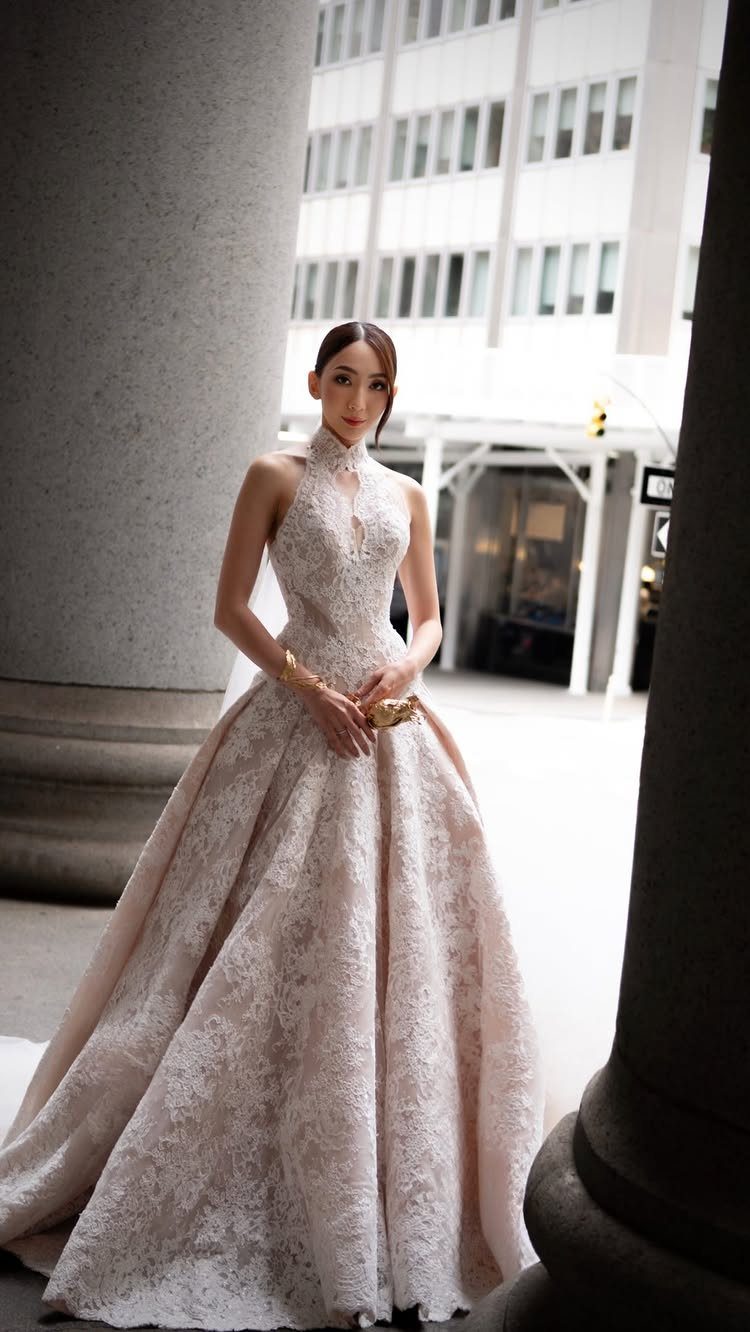 Church Wedding Dress: 10 Styles for the Ceremony 1 A woman in a high-neck lace wedding gown standing between large stone columns.