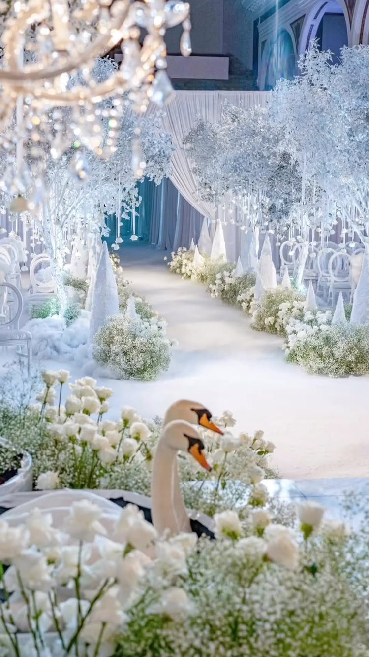 White frosted trees and flowers line a wedding aisle under a crystal chandelier.