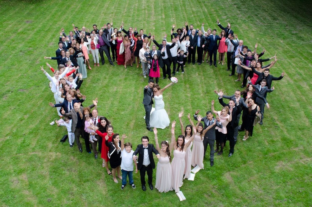 9 Family Wedding Picture Ideas for Every Group 7 Wedding guests and family members standing on a green lawn in a large heart shape formation.