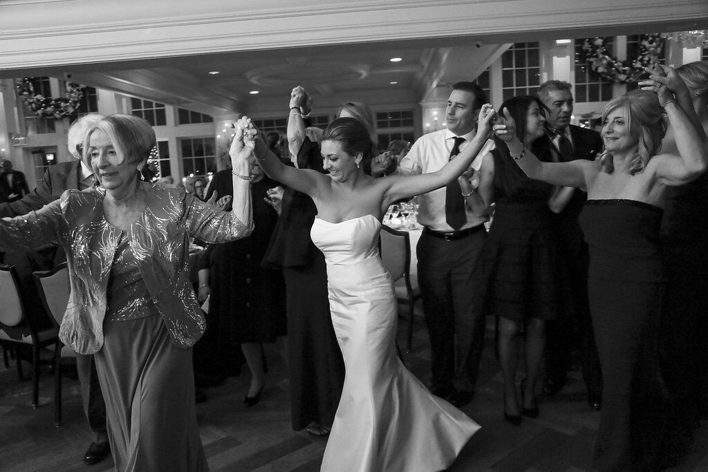 9 Family Wedding Picture Ideas for Every Group 9 A bride and several wedding guests dancing together in a circle during a reception.