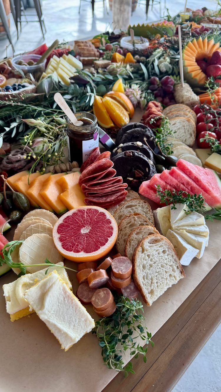 A large grazing table filled with assorted meats, cheeses, fruits, and breads.