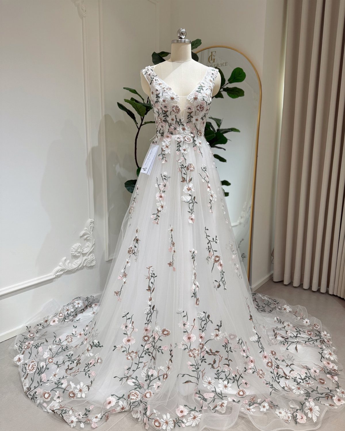 An A-line wedding dress with floral embroidery and a long tulle train on a mannequin.