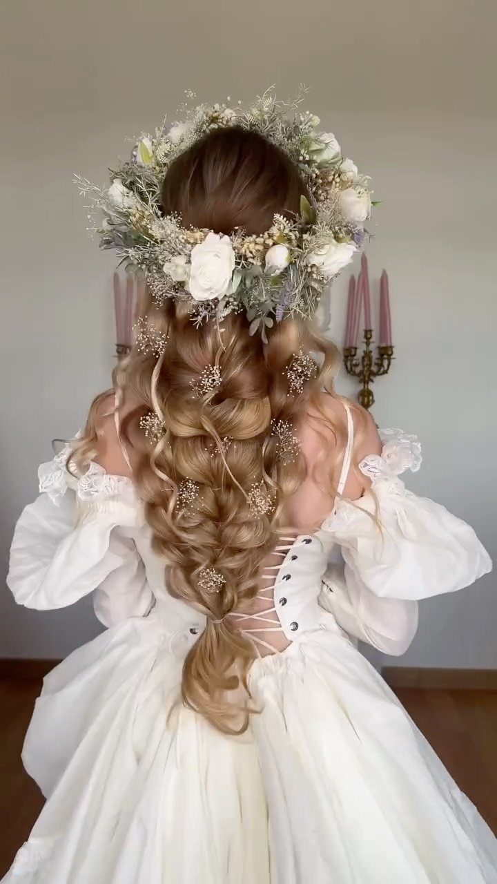 Woman in an ivory wedding dress with a floral crown and braided hair seen from behind.