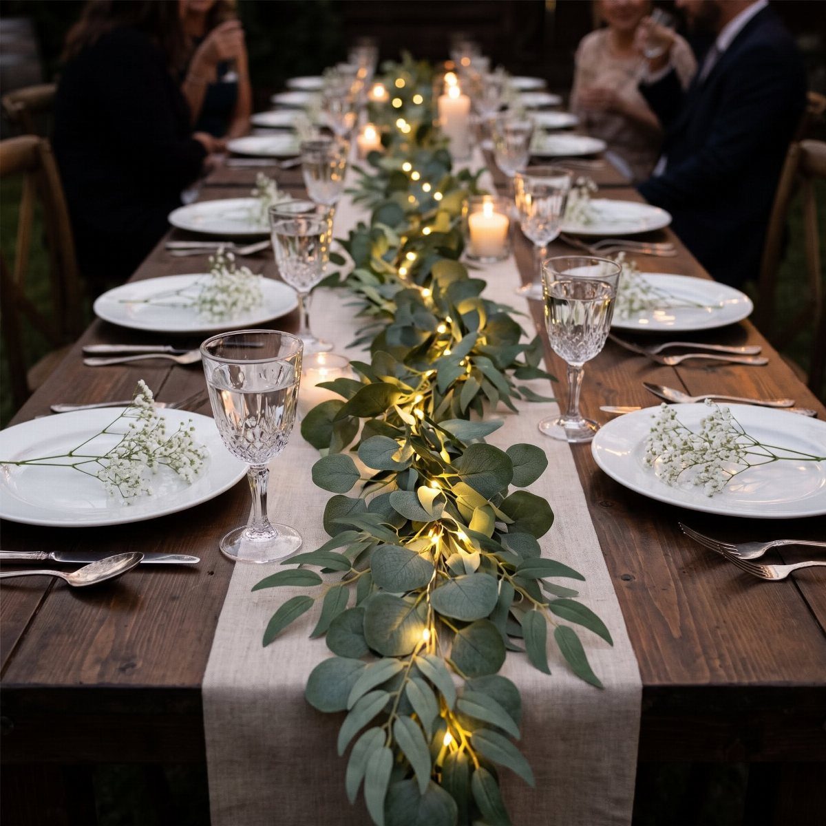 Eucalyptus greenery garland with glowing tea light candles running down a long wooden dining table.