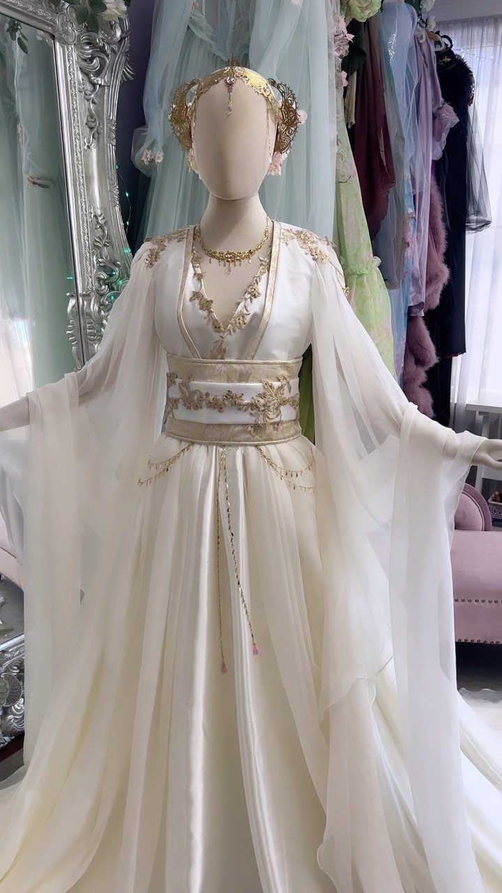 Ivory goddess wedding dress with flowing chiffon sleeves and gold embroidery on a mannequin.