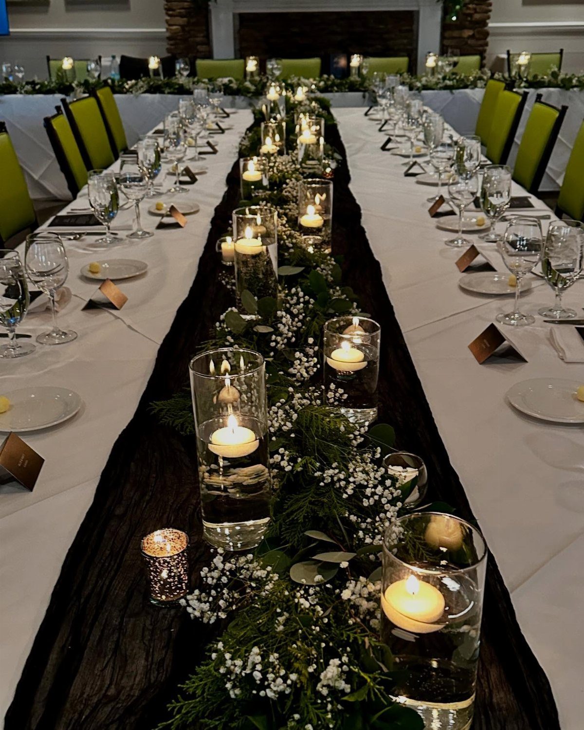 Greenery garland with floating candles in glass vases running down a long dining table.