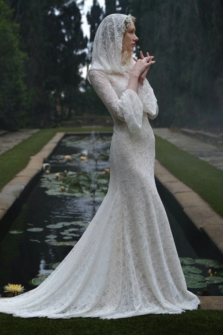 Hooded Wedding Dress: 6 Ideas from Vintage to Modern 4 A woman wearing a long-sleeved white lace wedding dress with a sheer lace hood.
