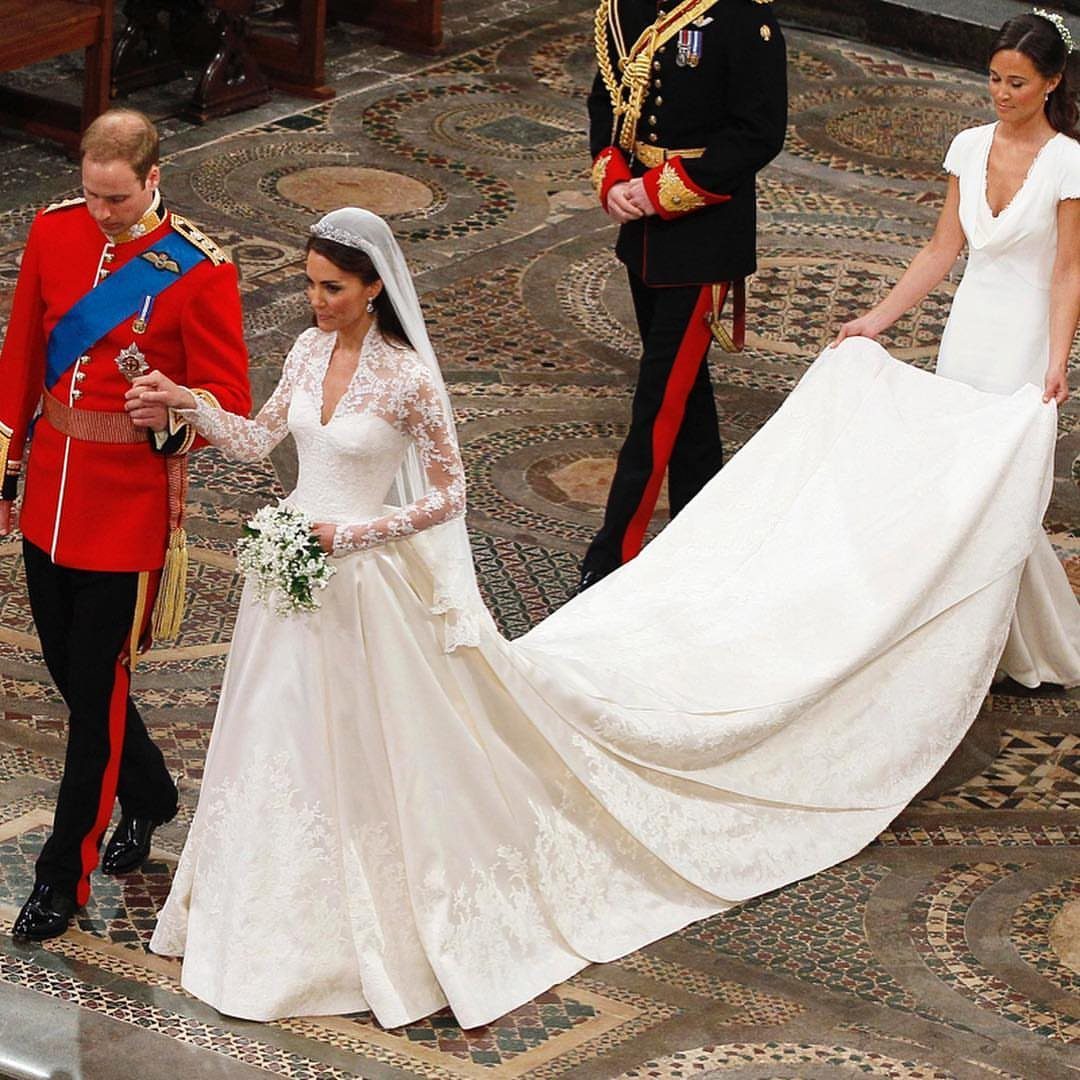 Iconic Wedding Dresses and 6 Stories They Still Tell 3 Kate Middleton walking in her lace wedding dress with a long train during her royal wedding.