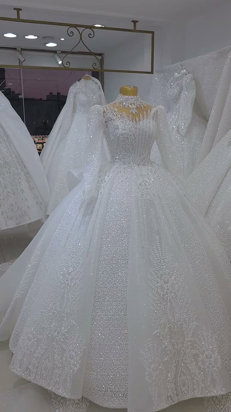 Lace Ball Gowns: 6 Silhouettes and Styles for Your Wedding 1 A white lace ball gown wedding dress with long sleeves displayed on a mannequin.