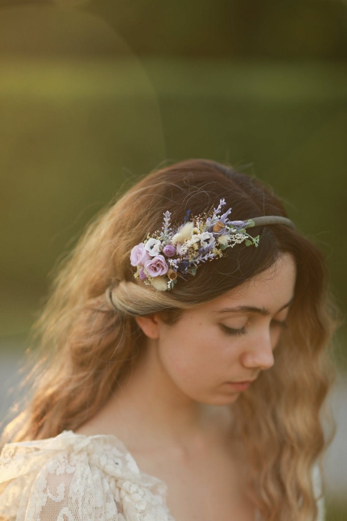 A young woman wearing a delicate floral crown made of lavender and small purple flowers.