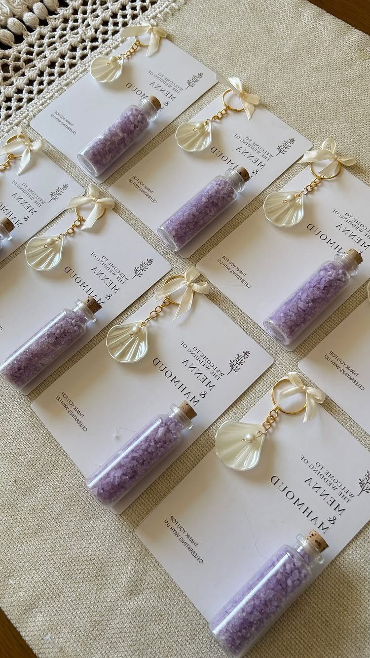 Small glass vials filled with purple lavender salt crystals attached to white cards with seashell charms.