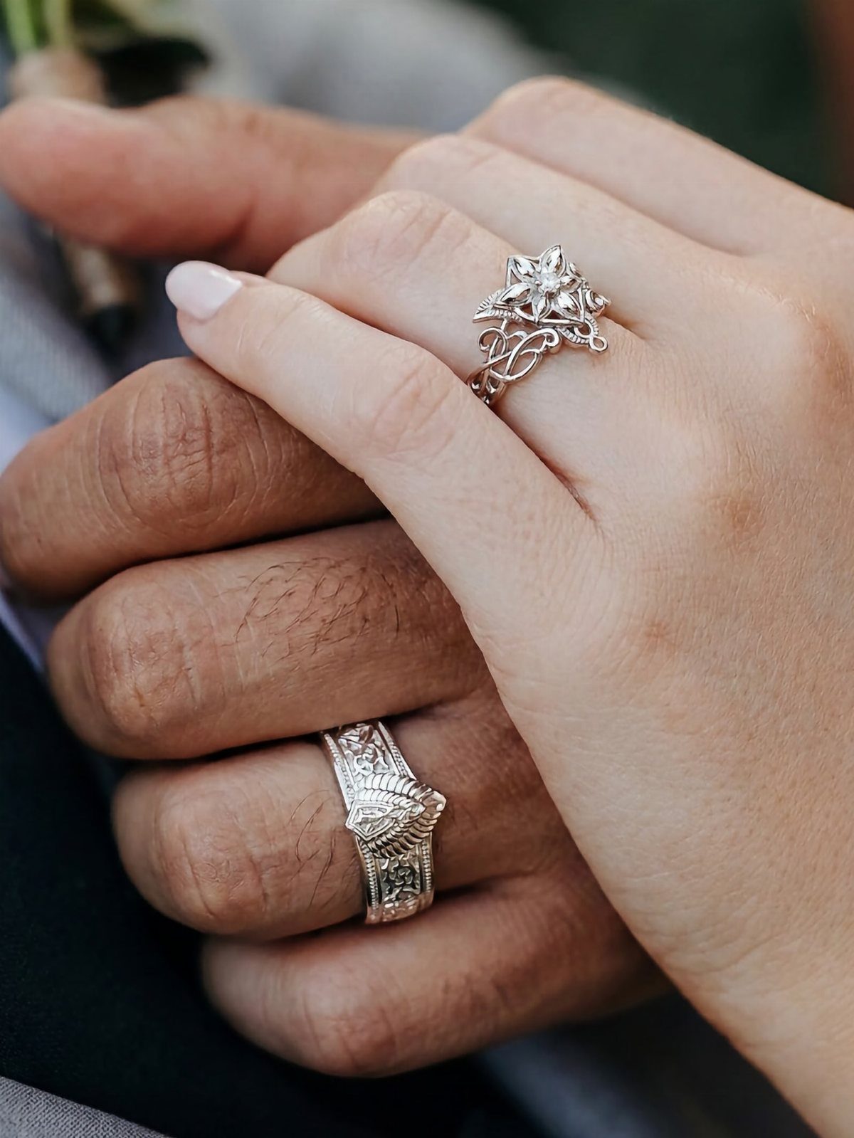 Two hands joined together featuring intricate silver rings with organic, elven-inspired designs.