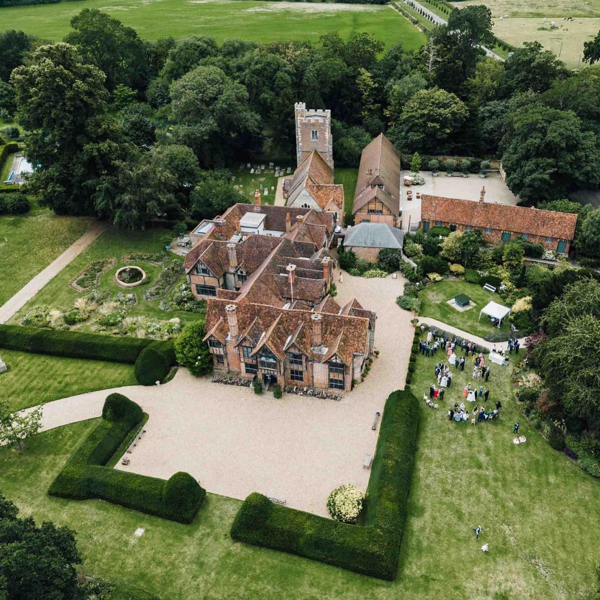 Mansion Wedding Venue Ideas: 17 Estate Settings for 2026 5 Aerial view of a large brick mansion surrounded by manicured green lawns and hedges.