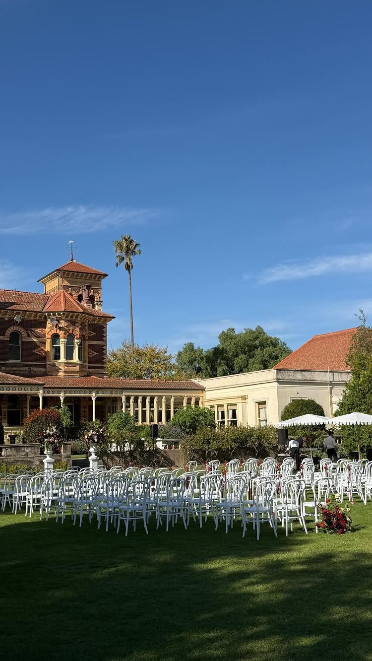 Mansion Wedding Venue Ideas: 17 Estate Settings for 2026 12 White wedding chairs arranged on a green lawn facing a large historic mansion under a blue sky.