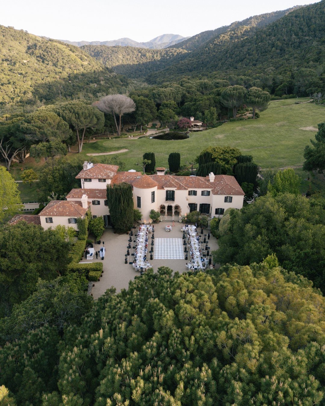 Mansion Wedding Venue Ideas: 17 Estate Settings for 2026 14 Aerial view of a large Mediterranean mansion with banquet tables set up in the courtyard.