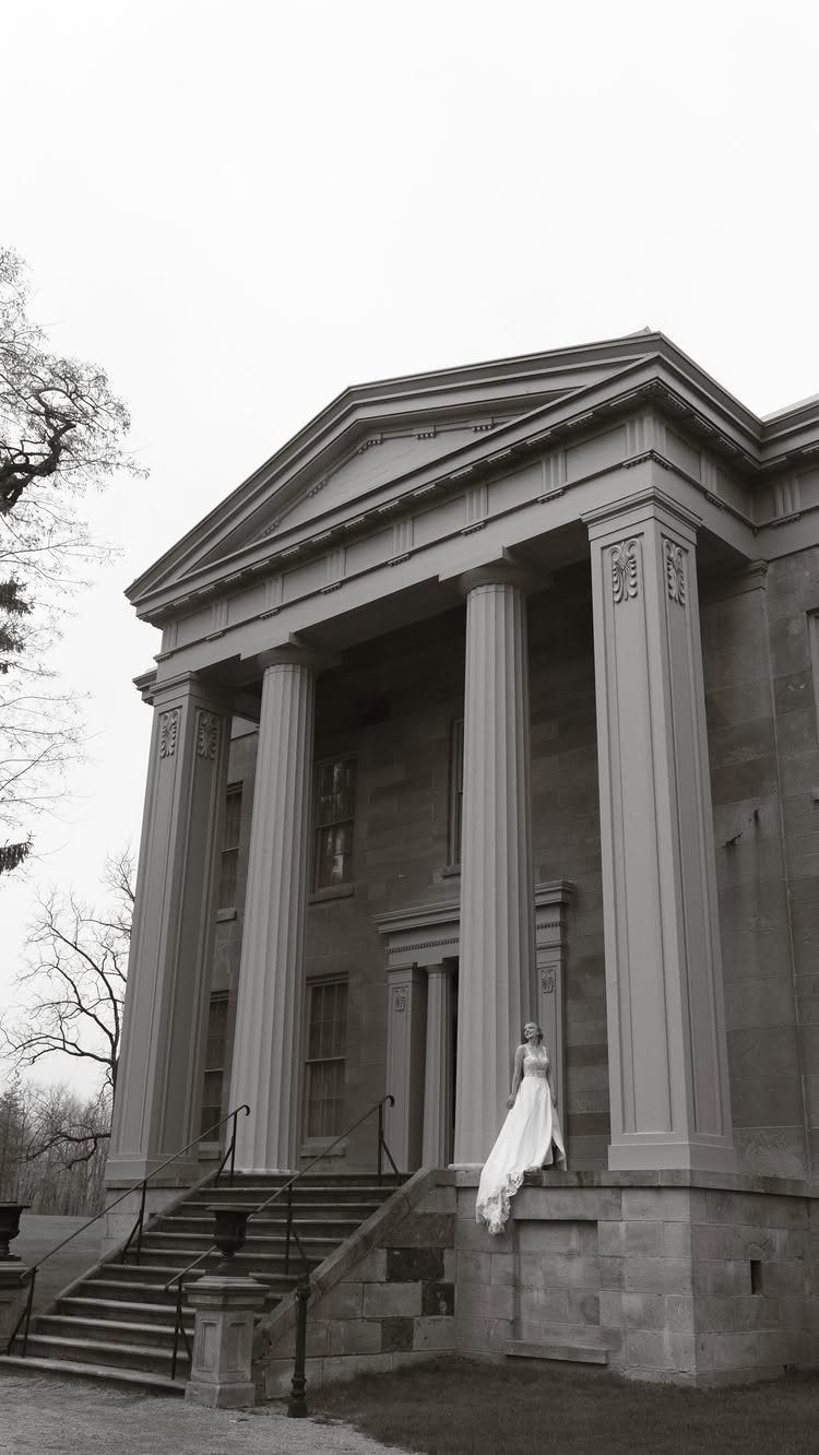 Mansion Wedding Venue Ideas: 17 Estate Settings for 2026 8 A bride in a white gown standing on the grand stone steps of a neoclassical mansion.
