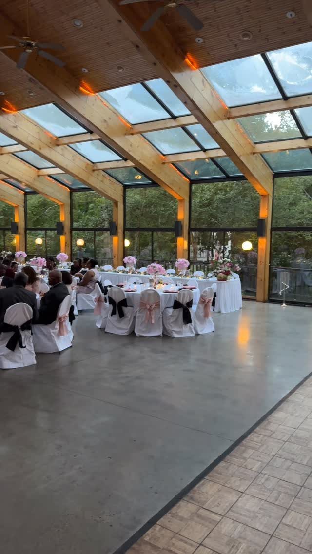 15 Most Beautiful Wedding Venues for 2026 12 Wedding reception tables with white linens and pink flowers inside a glass-walled pavilion.