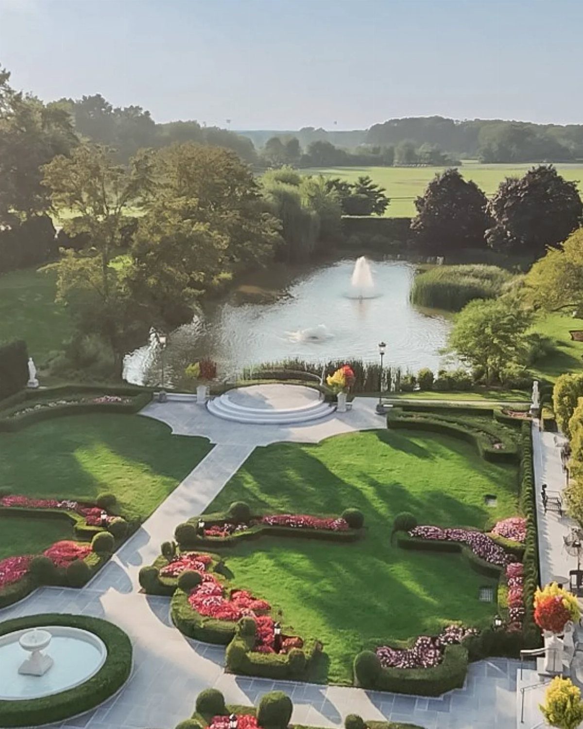 15 Most Beautiful Wedding Venues for 2026 2 Manicured estate gardens with symmetrical flower beds, stone paths, and a large pond with a fountain.