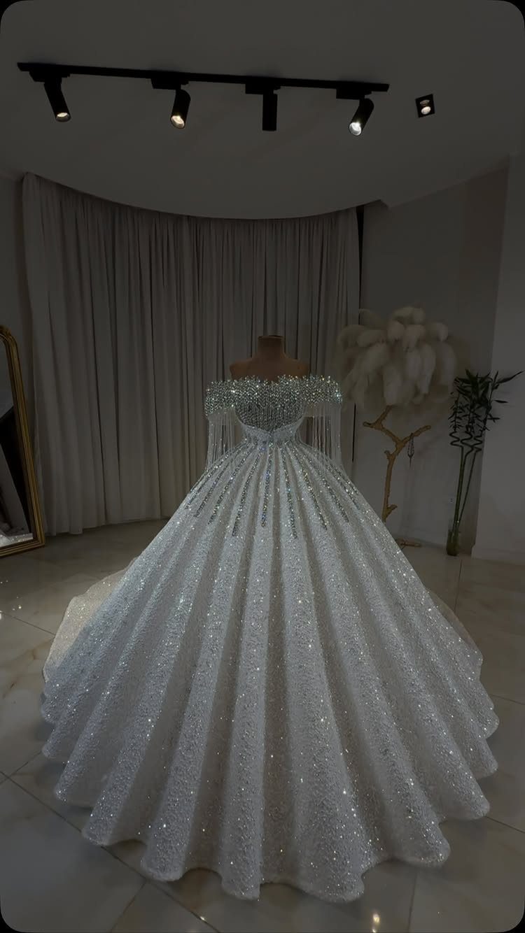 A shimmering white wedding gown with heavy crystal embellishments on a mannequin.