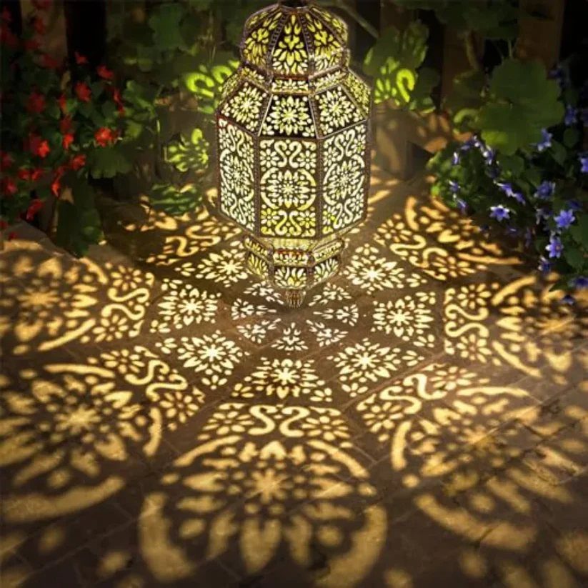 An ornate glowing lantern casting intricate light patterns onto a stone ground surrounded by greenery.