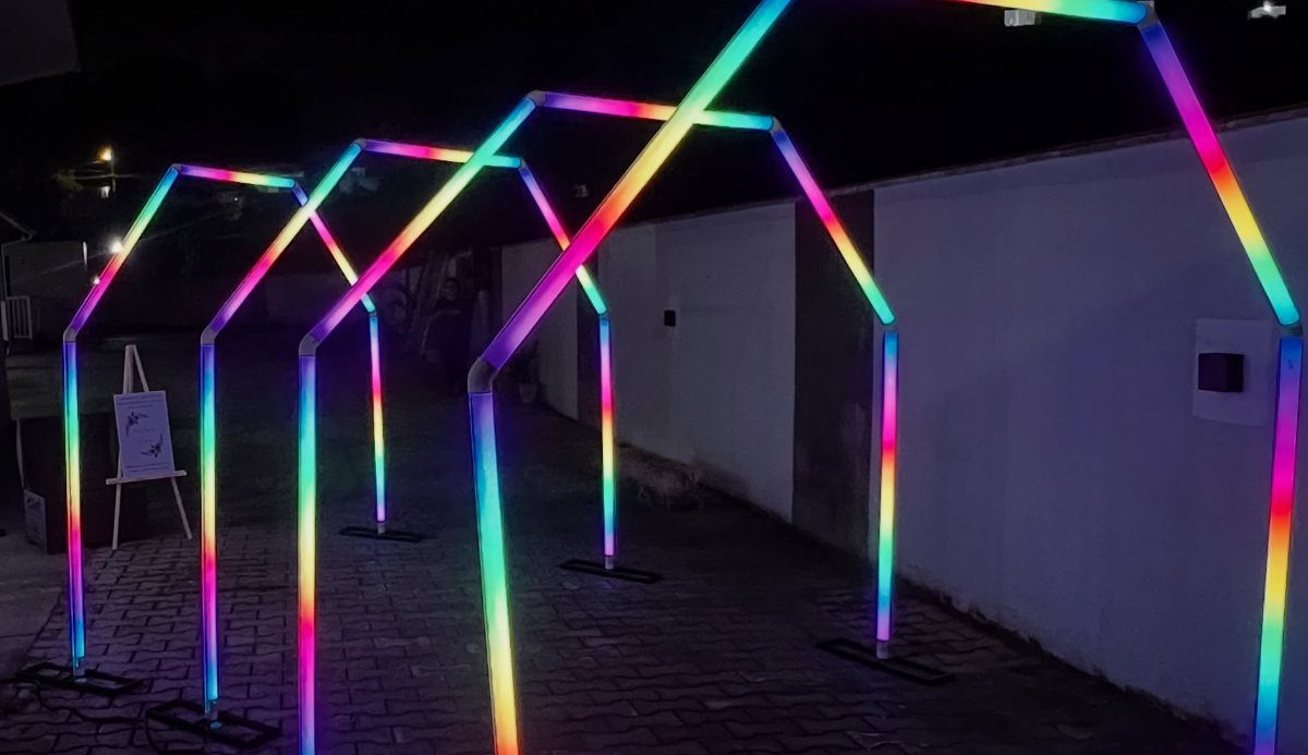 Glowing neon geometric archways lined up along a dark outdoor walkway at night.