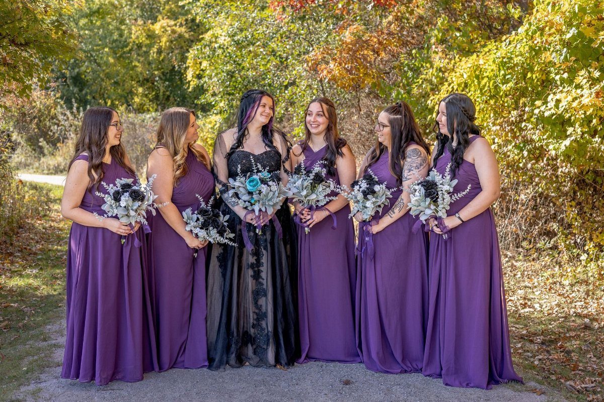 Purple and Black Wedding Theme: 8 Ideas That Actually Work 6 Six women in purple and black dresses holding floral bouquets standing outdoors in front of trees.