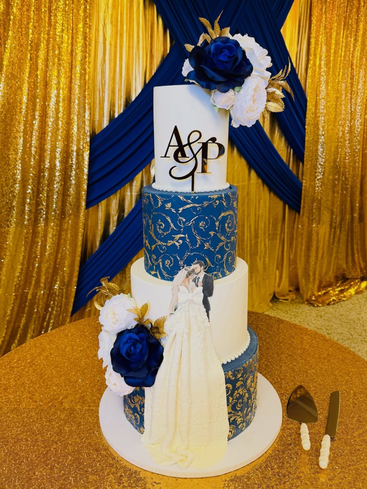 A tiered wedding cake with royal blue patterns, white frosting, and large blue and white roses.