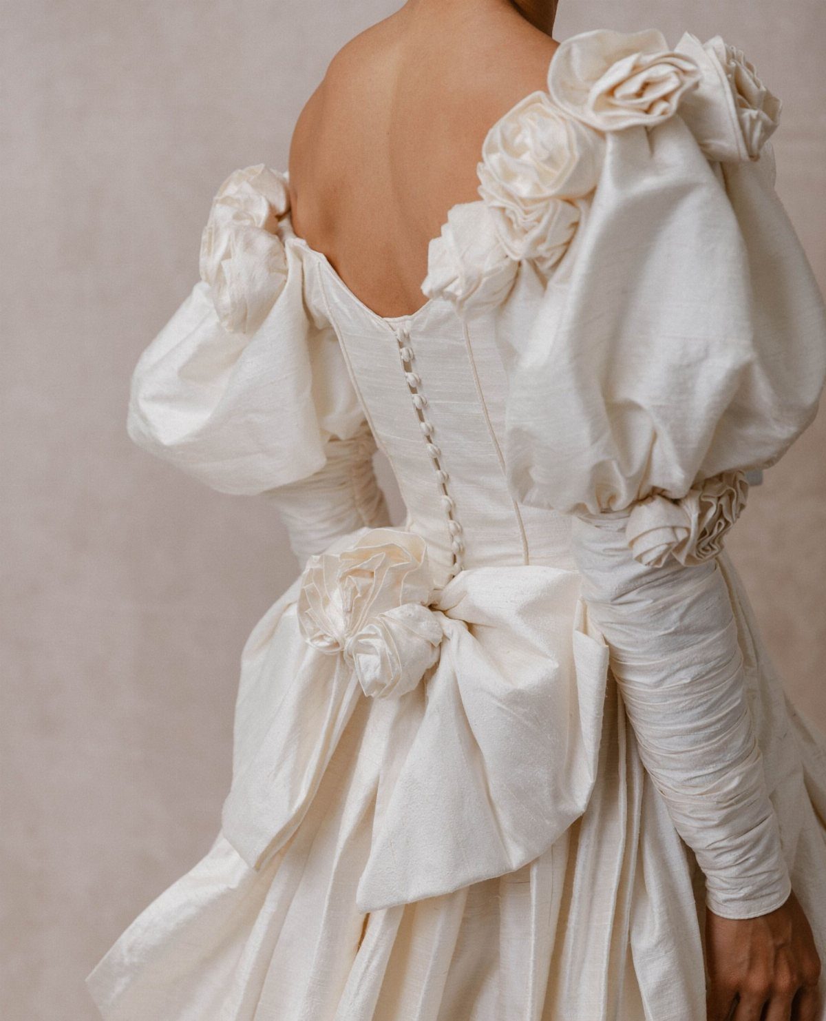 Ivory wedding dress with large puffed sleeves and fabric rose embellishments on a person.