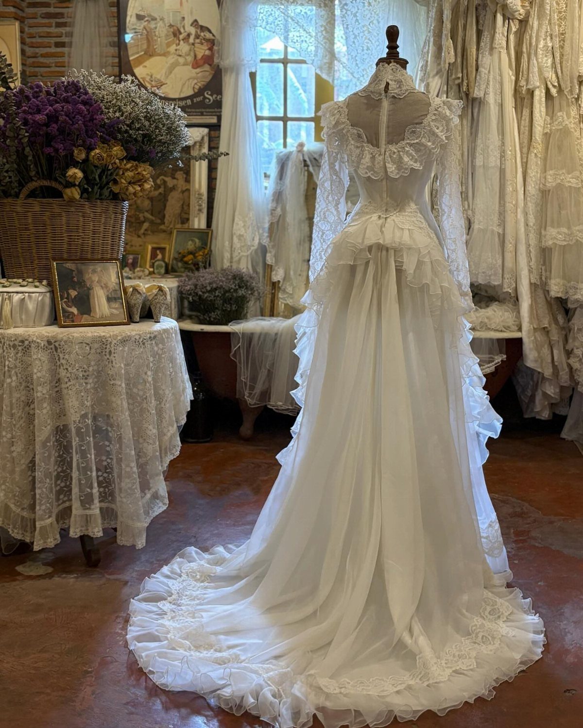 An ivory lace Victorian wedding dress with a ruffled skirt displayed on a mannequin.