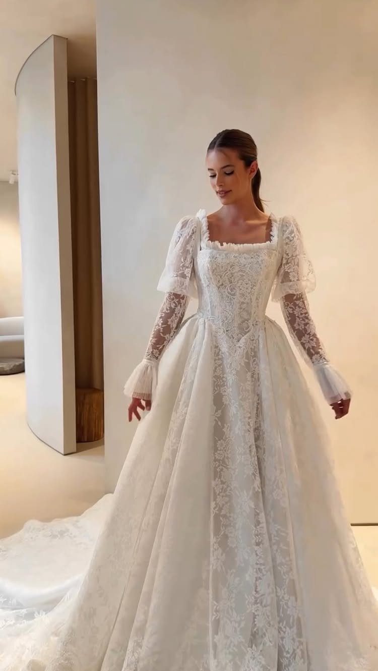 Woman wearing a vintage white lace wedding dress with long sleeves and a flowing A-line skirt.