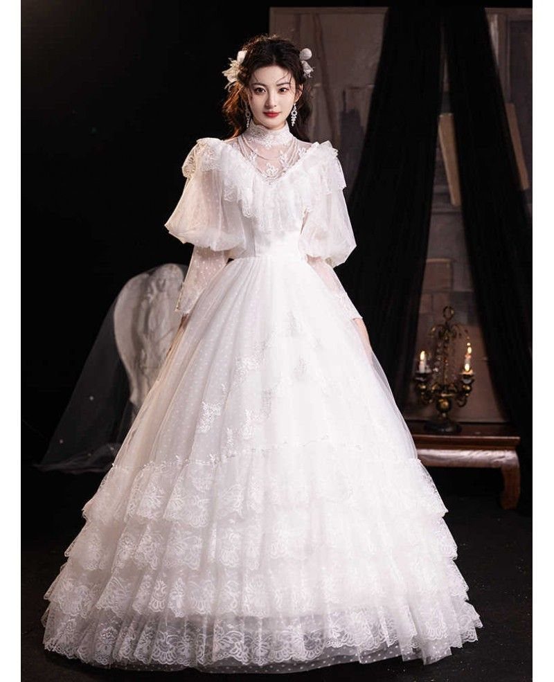Woman in a white vintage wedding dress with puff sleeves and a lace bodice.