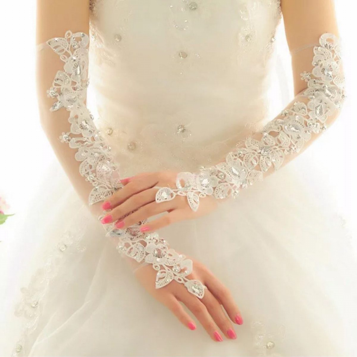 Lace fingerless bridal gloves with floral embroidery worn over a white wedding dress.