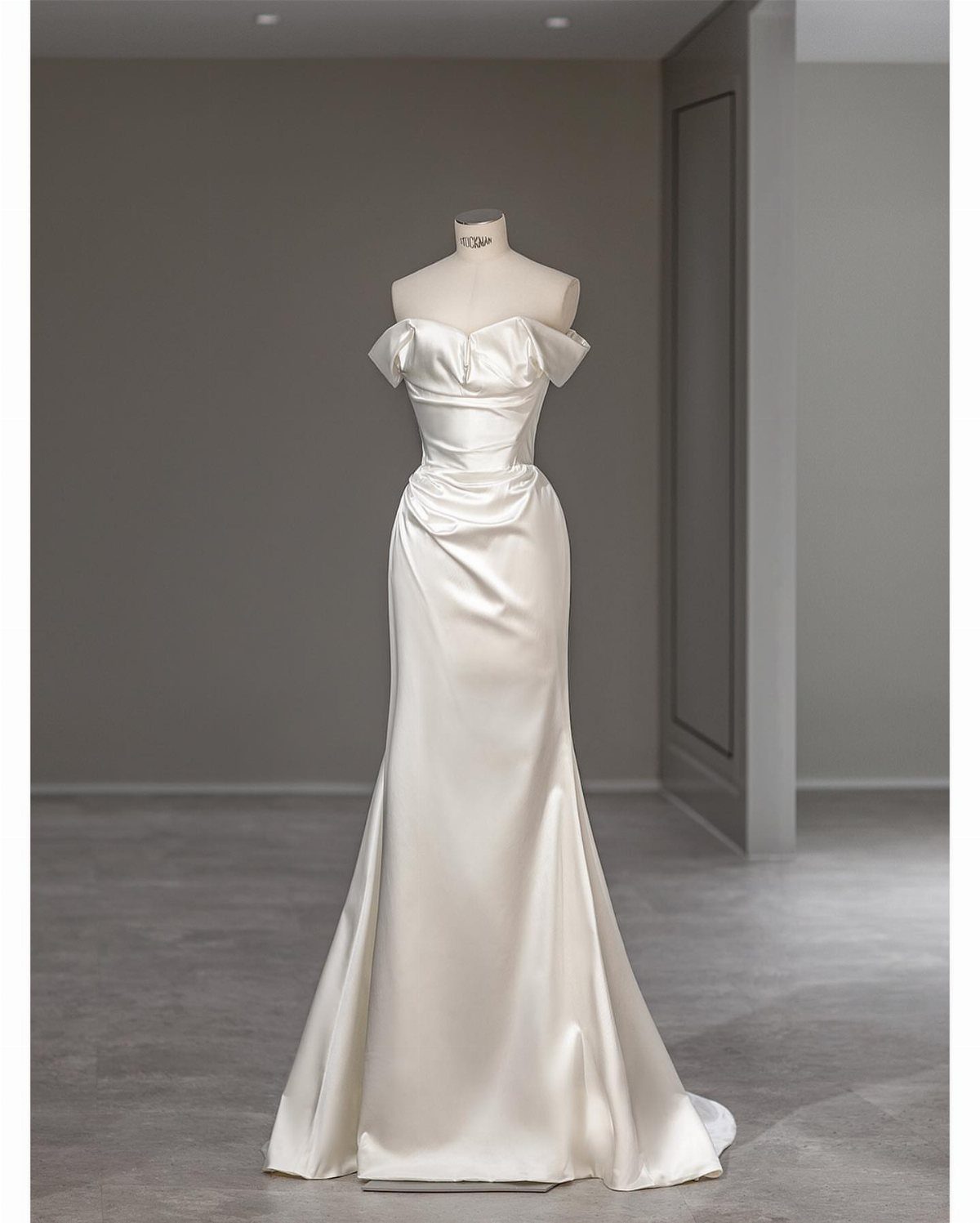Wedding Dress Fabrics: 4 Photos of Silk, Lace, Satin and Tulle 3 A white satin wedding dress with off-the-shoulder sleeves displayed on a mannequin.