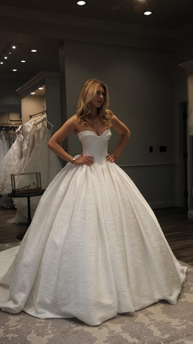 Wedding Dress Trends: 10 Looks for 2026 10 A woman posing in a white strapless ballgown wedding dress with a structured bodice.