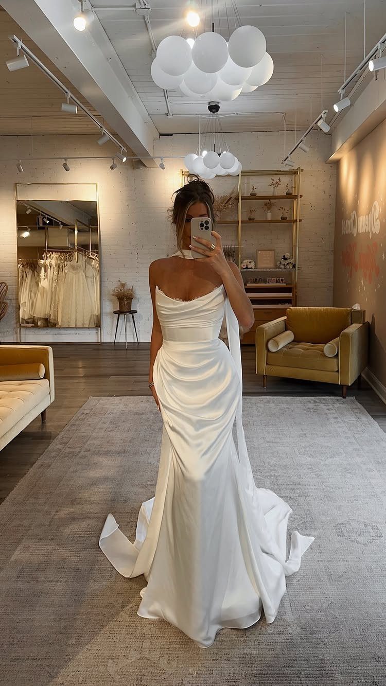 5 Wedding Dress with Bodice Ideas from Corset Gowns to Draped Satin 3 Woman in a white satin wedding dress with a draped bodice taking a mirror selfie.