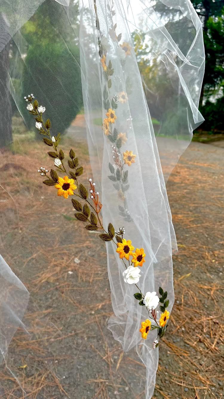 A white sheer bridal veil featuring embroidered yellow sunflowers and small white blossoms.