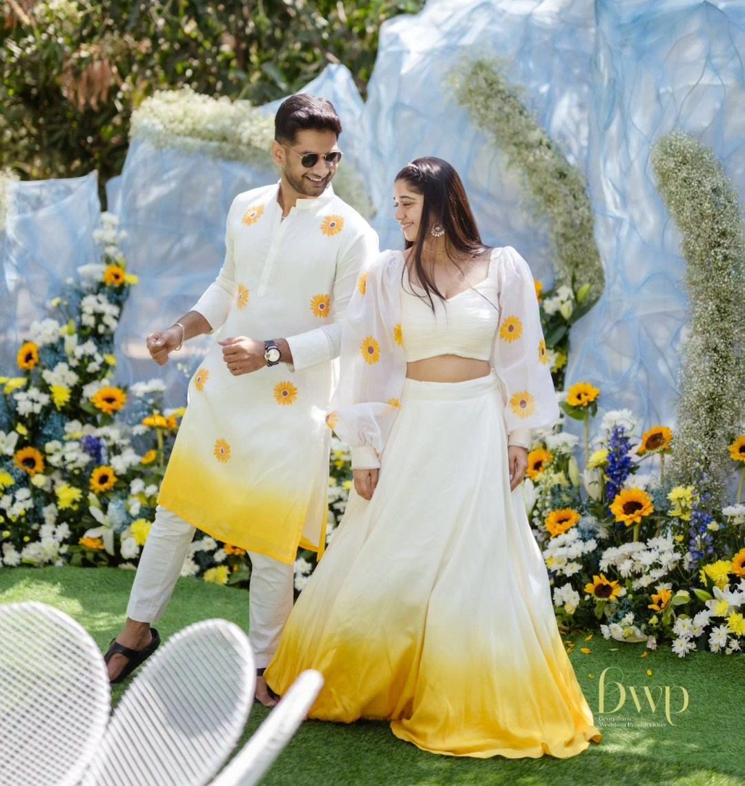 A man and woman wearing white and yellow sunflower patterned wedding attire outdoors.